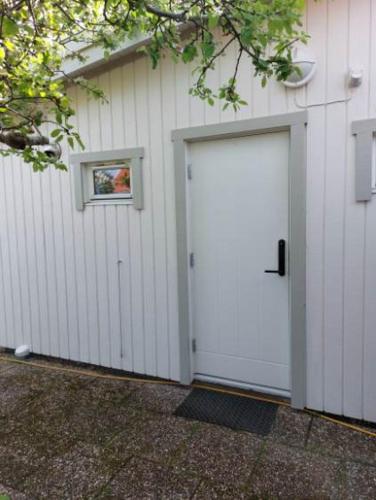 a white garage with a door next to a building at Lugnt och centralt in Strömstad