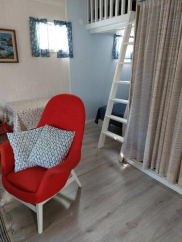 um quarto com uma cadeira vermelha e uma escada em Lugnt och centralt em Strömstad