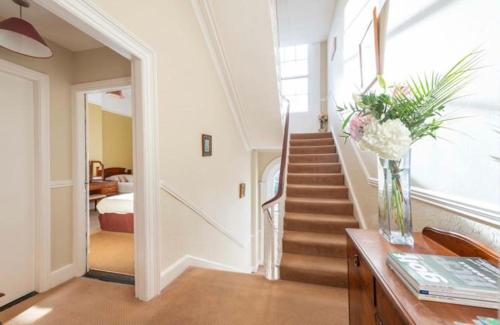 un pasillo con una escalera y un jarrón de flores sobre una mesa en Abbeyleigh House, en Dublín