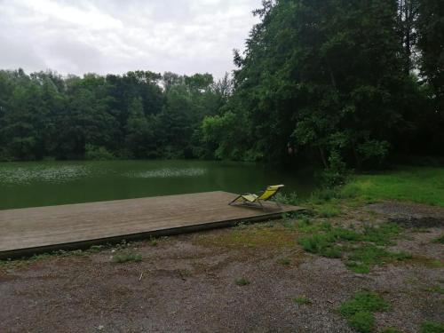 una silla amarilla sentada en un muelle junto a un lago en Cottage autour de l'étang 79, en Bourbourg