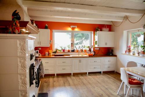 a kitchen with white cabinets and an orange wall at Komfortowy Dom w Chmurach in Dydnia
