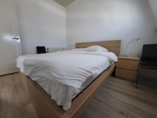 a bedroom with a white bed with a desk and a chair at Beautiful spacious appartment at top location The Hague in The Hague