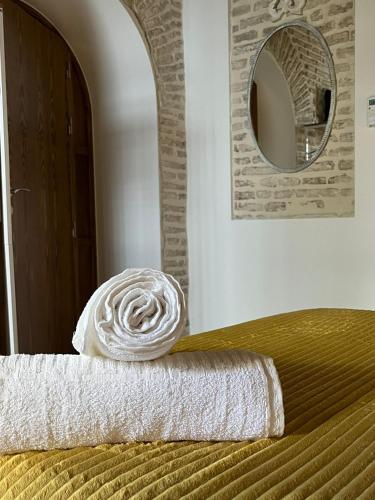 a stack of towels sitting on a bed with a mirror at Clarisas Suites in Carmona