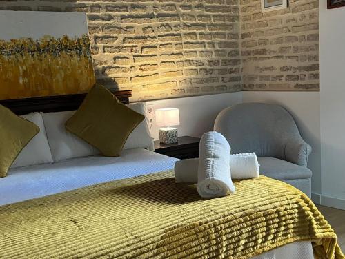 a bedroom with a bed and a chair with towels on it at Clarisas Suites in Carmona