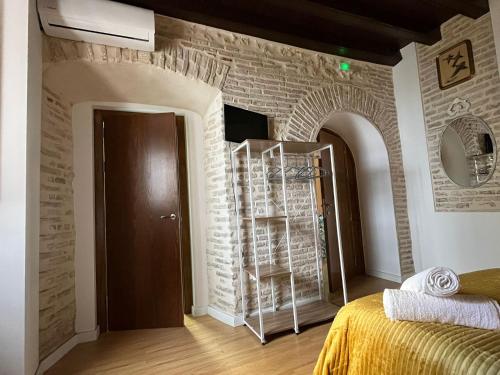 a room with a brick wall with a bed and a mirror at Clarisas Suites in Carmona