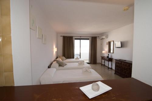 ein Hotelzimmer mit 2 Betten und einem Tisch in der Unterkunft Apartamentos Mestret in Sant Antoni de Portmany