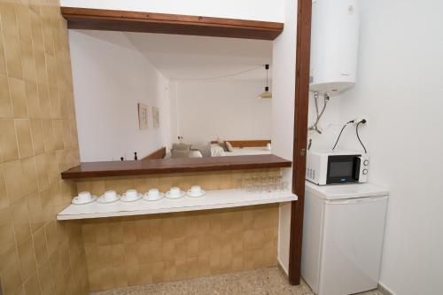 eine kleine Küche mit einer Spüle und einer Mikrowelle in der Unterkunft Apartamentos Mestret in Sant Antoni de Portmany