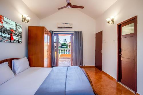 1 dormitorio con 1 cama y puerta a un balcón en 'Golden Coral' 2bhk Benaulim Beach villa Goa, en Margao