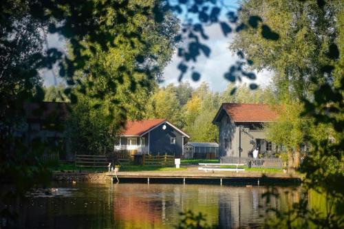 ein Haus am Ufer eines Sees mit einer Anlegestelle in der Unterkunft Cottage autour de l'étang 79 in Bourbourg