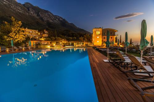 a large swimming pool with chairs and a mountain at Natur Resort Panorama in Malcesine