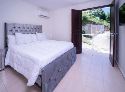- une chambre avec un grand lit et une porte coulissante en verre dans l'établissement Hotel porto escondido, à Santa Bárbara de Samaná