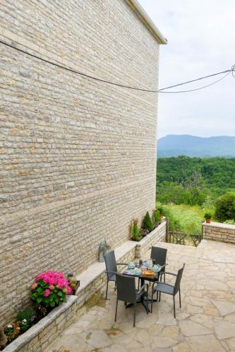 a patio with a table and chairs next to a brick wall at The five keys in Monodendri