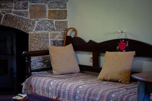 1 cama con 2 almohadas y pared de piedra en Μουριές, en Kamariótis