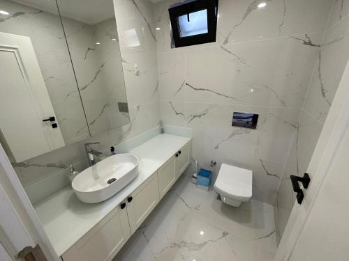 uma casa de banho branca com um lavatório e um WC em Özel Havuzlu Muhteşem Villa em Aksu