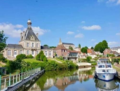 a boat docked in a river in front of a building at Gite Le Long de l'eau in Long