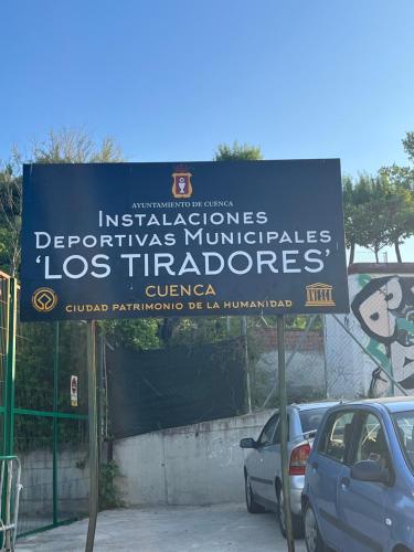 a sign in a parking lot with cars parked at ALOJAMIENTO LOS DINOSAURIOS in Cuenca