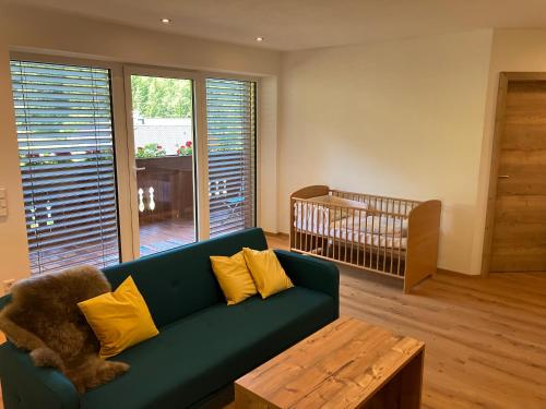 a living room with a green couch and a crib at Mahdgut 