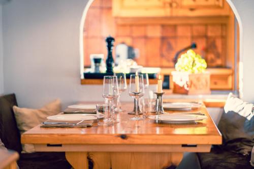 a wooden table with wine glasses and plates on it at Casa Nonna in Lenzerheide