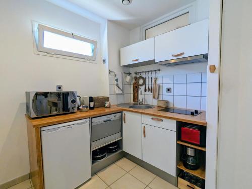 a small kitchen with white cabinets and a microwave at "Côté Lagon" à deux pas du lagon in Saint-Paul