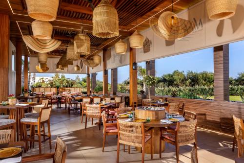 a restaurant with tables and chairs and large windows at NissiBlu Beach Resort in Ayia Napa