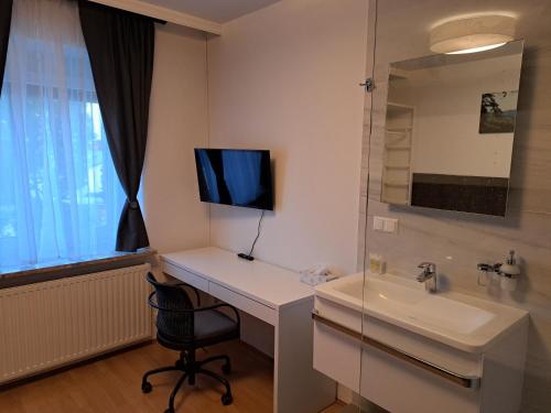 a bathroom with a sink and a desk with a television at Flataid Gästehaus Graschi - Steinbergstraße in Graz