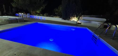 a blue swimming pool at night with two chairs at EXQUISITE GOLF VILLA with Sea, 8Tee, Green Views, in Aphrodite Hills Golf Resort in Kouklia