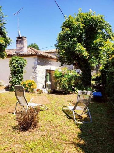 two chairs sitting in the grass in front of a house at Gîte La Petite Longère in Septfonds