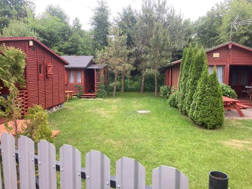 a backyard with a white picket fence and two cottages at Sielska Chatka Chłopy in Sarbinowo