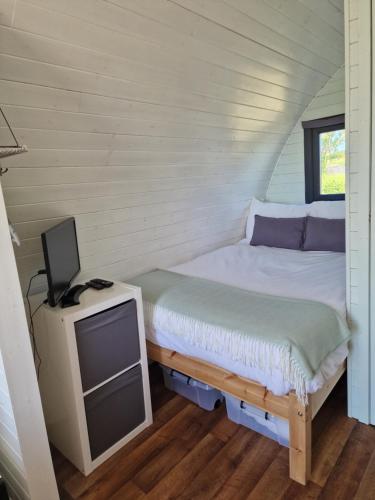 a small bedroom with a bed and a tv at Jerusalem Farm Pods in Tranent