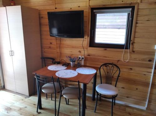 jadalnia ze stołem, krzesłami i telewizorem w obiekcie Arkadia Domki w Dziwnowie