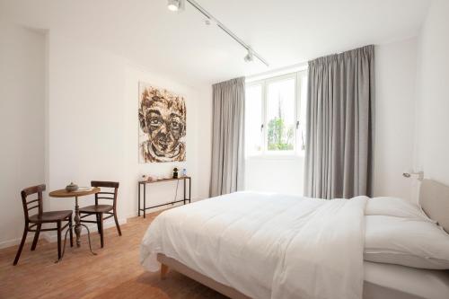 1 dormitorio blanco con 1 cama, mesa y sillas en Le Charbonnage, en Genk