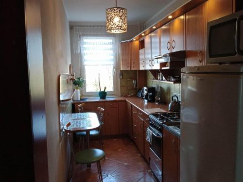 eine Küche mit Holzschränken, einem Tisch und einem Kühlschrank in der Unterkunft Apartament na Ogrodach in Kołobrzeg
