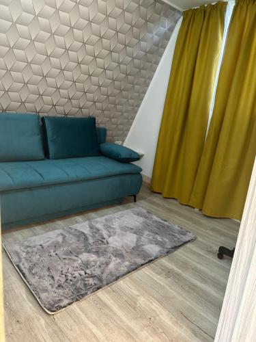 - un salon avec un canapé bleu et des rideaux jaunes dans l'établissement Casa de lemn 2,Tip A, à Corbu