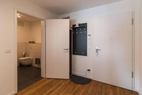 La salle de bains est pourvue de toilettes et d'une porte blanche. dans l'établissement CityHome Christopher CHC, à Kulmbach