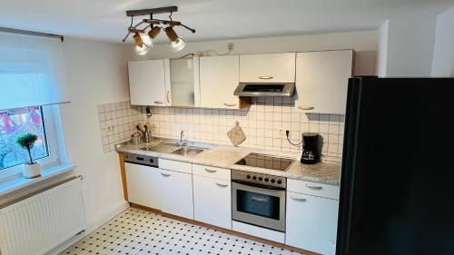 una cucina con armadi bianchi e piano cottura di Mitten in den Weinbergen a Sommerhausen