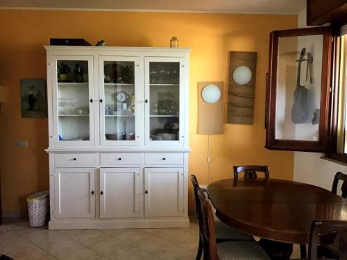 une grande armoire blanche dans une salle à manger avec une table dans l'établissement Mandorli, à Su Forti