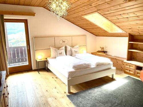 ein Schlafzimmer mit einem weißen Bett und einem Kronleuchter in der Unterkunft Chalet Bernardi Apartments in St. Ulrich in Gröden