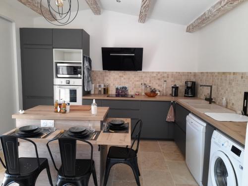 cocina con mesa de madera y sillas negras en Gîte en Cévennes en Saint-Martin-de-Valgalgues