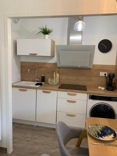 a kitchen with white cabinets and a sink and a table at Authentique &; Design in Saint-Lary-Soulan