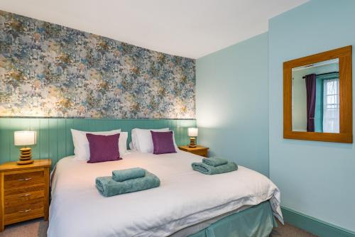 a bedroom with a large white bed with purple pillows at The Queens in Carlisle