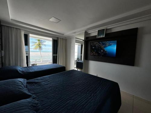 a bedroom with a bed and a flat screen tv at FHF Blue Suites in João Pessoa