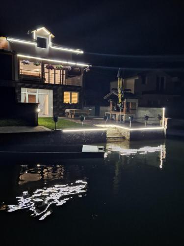 a house lit up at night with a body of water at Vila Gavrić in Zvornik