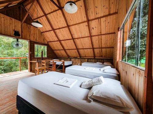 three beds in a room with a wooden ceiling at Rancho Hanna - Pousada, Camping e Comidaria in Iporanga