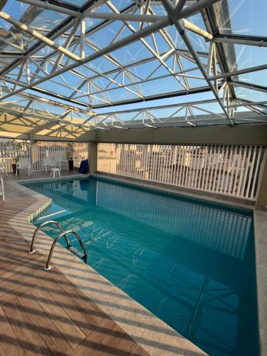 a large swimming pool with a glass ceiling at NOVO pitangueiras service 2, dois dormitórios, 100 m da praia, duas vagas de garagem, completo in Guarujá