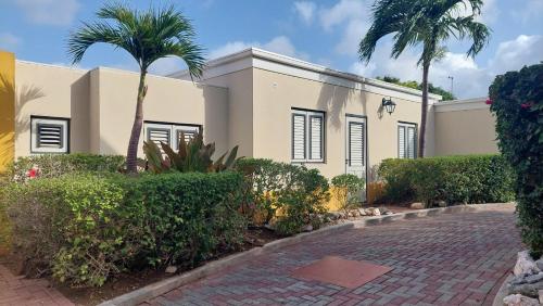 a house with palm trees and a brick driveway at Landhuis Bona Vista in Willemstad