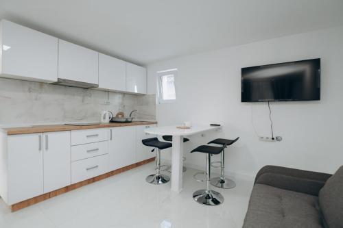 eine Küche mit weißen Schränken sowie einem Tisch und Stühlen in der Unterkunft Apartmani Otašević in Kladovo