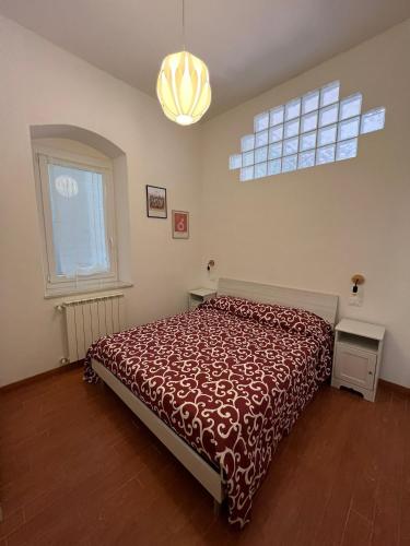 a bedroom with a bed with a red comforter and a window at speZialhouse - Centro Storico & Cinque Terre in La Spezia