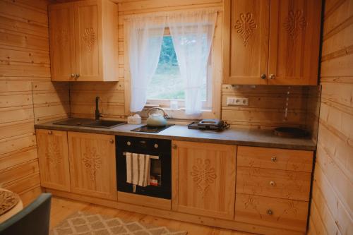 cocina con armarios de madera, fregadero y ventana en Domek na Groniku, en Zubrzyca Górna