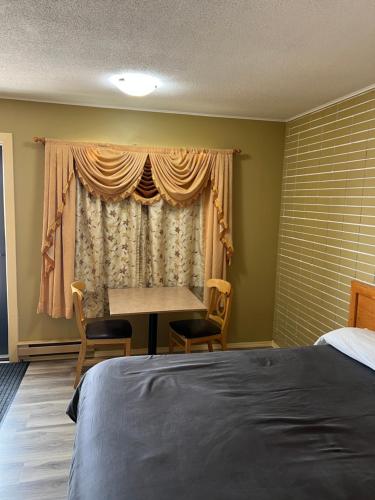 a bedroom with a bed and a table and a window at Motel 66 in Transcona