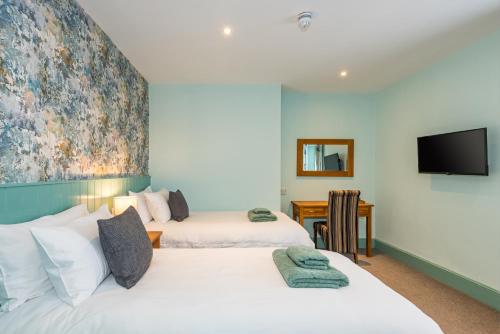 two beds in a room with a tv on the wall at The Queens in Carlisle